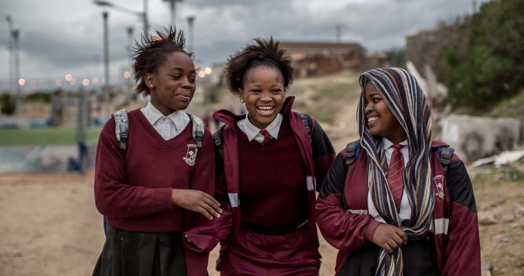 Three smiling girls walk to school together